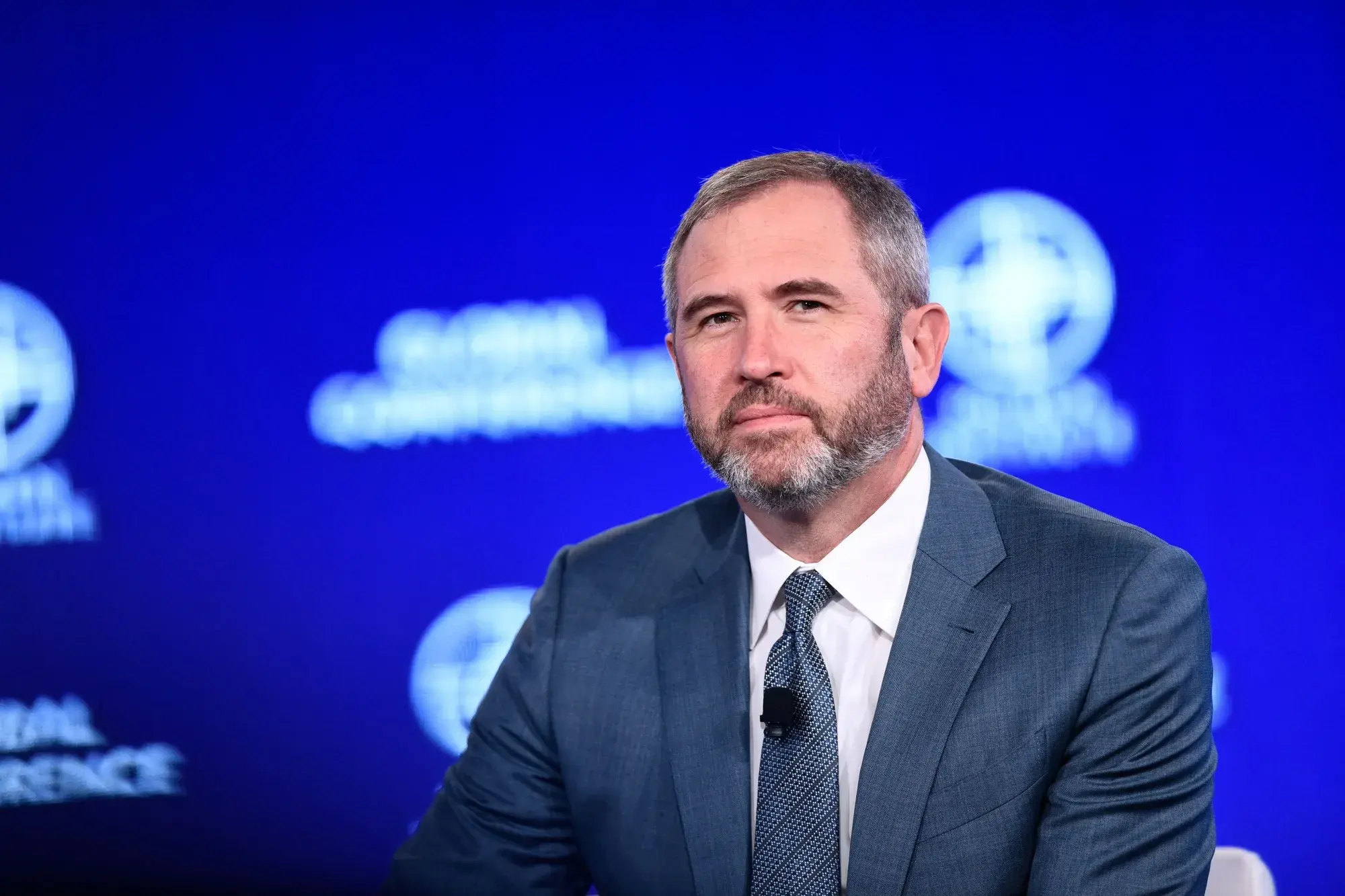 Brad Garlinghouse speaking at a conference with a blue background.