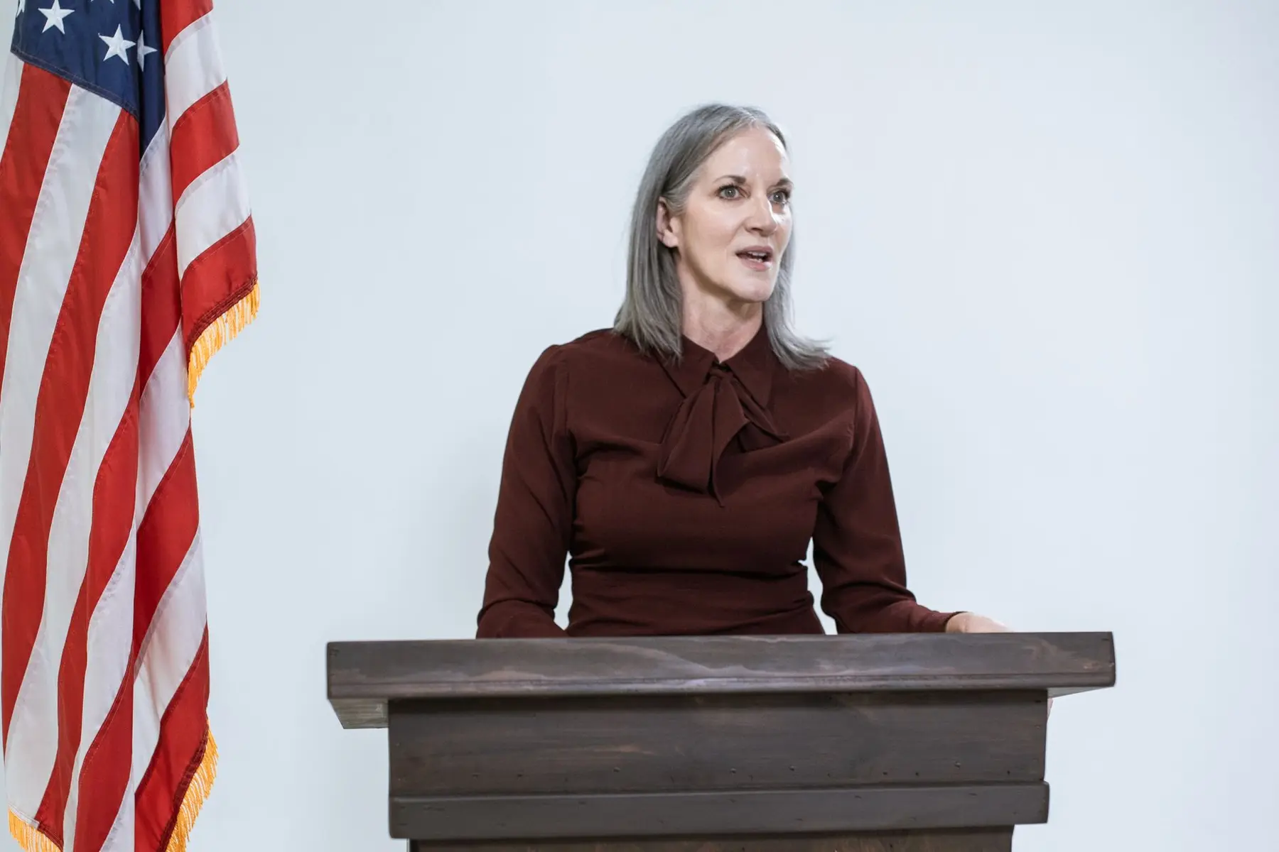 Senator Cynthia Lummis speaking at a wooden podium next to an American flag