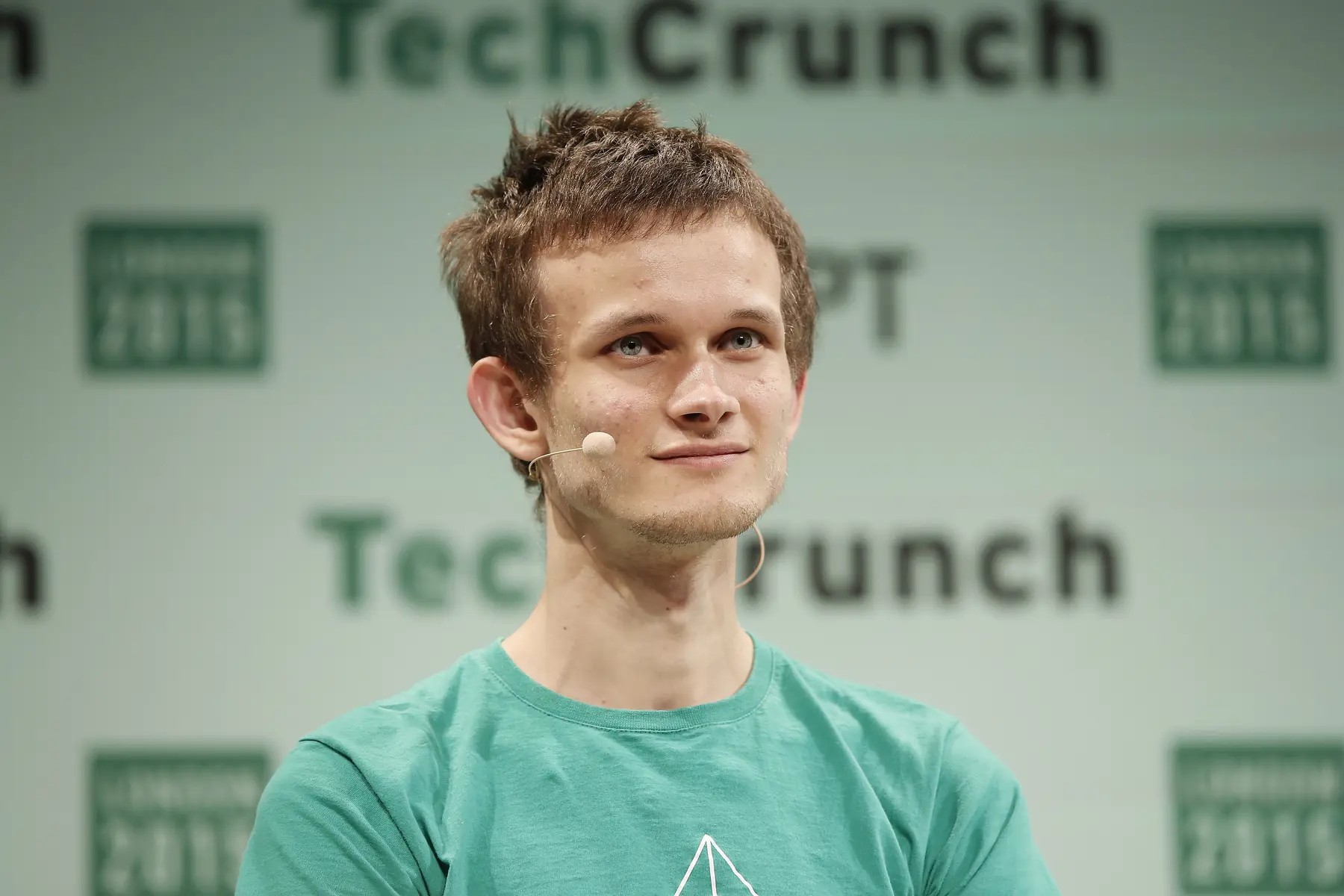Vitalik Buterin speaking at TechCrunch London 2015, wearing a green t-shirt.