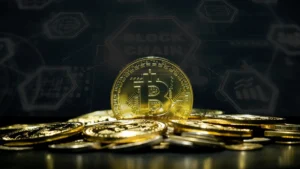 A stack of gold-colored Bitcoin coins with a digital blockchain graphic in the background.