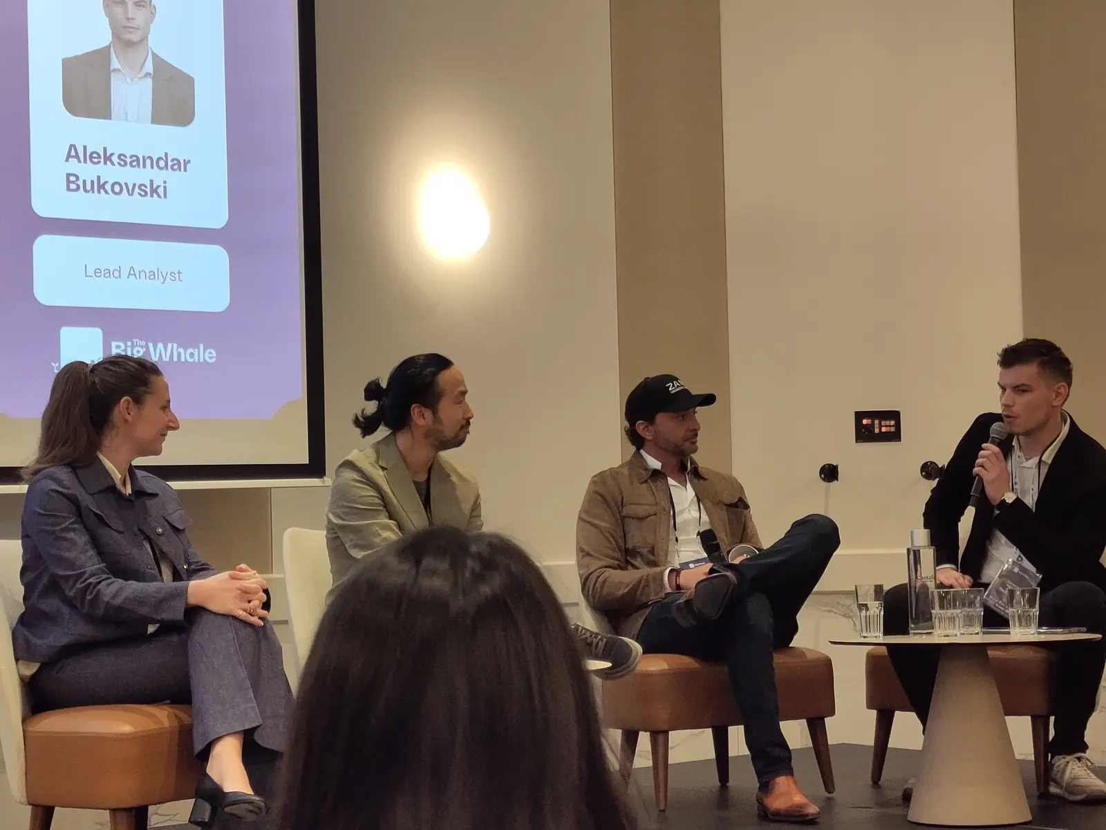 A panel discussion featuring four people seated on stage during an event.