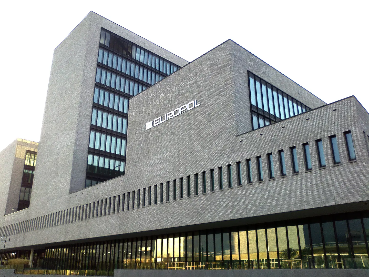 Exterior view of the Europol headquarters building in The Hague, featuring the Europol logo on a grey brick wall.