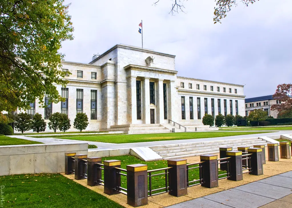 The white marble exterior of the Federal Reserve building in Washington D.C. under a cloudy sky.